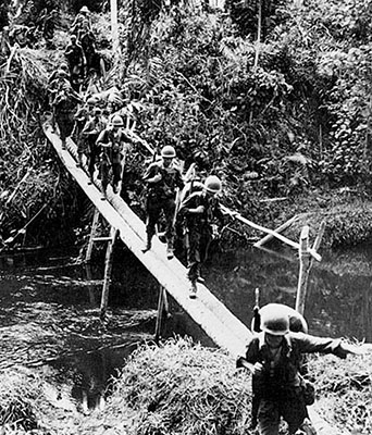 Troops of the 32nd Infantry Division cross a bridge in the jungle during the battle of Buna in New Guinea, November 1942. The 32nd was a Sixth Army unit in the Alamo Force.
