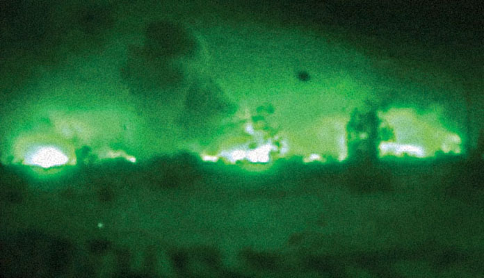 Thermal image of airstrikes lighting up the night sky.