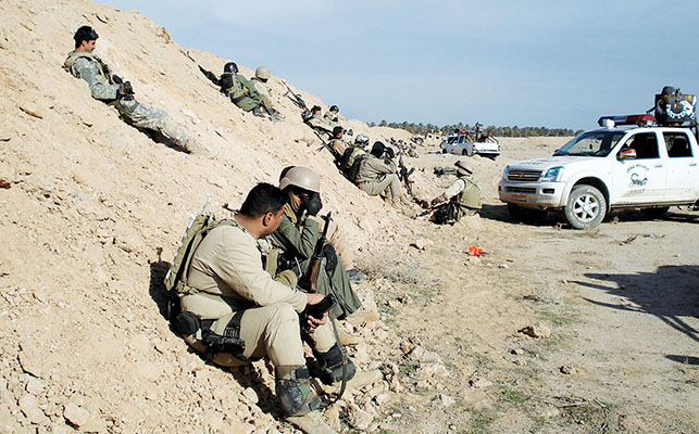 Dismounted Hilla SWAT police relax against the southern berm during a lull in the fighting.