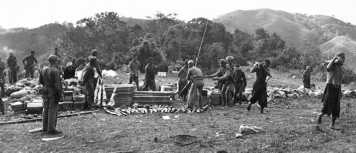 An OSS Area #1 group unpacks a supply drop for easier transportation in late 1944. The hills in the background give a good indication of the type of terrain over which the drop aircraft had to fly in order to deliver their cargo.