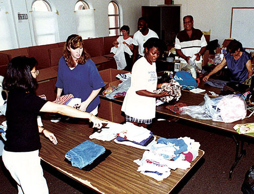 Civilian and military volunteers sort through clothing donated on Guam. The local community donated $650,000 worth of clothing, household items, toiletries, toys, and other things, as well over 40,000 volunteer hours during the six months of the operation.