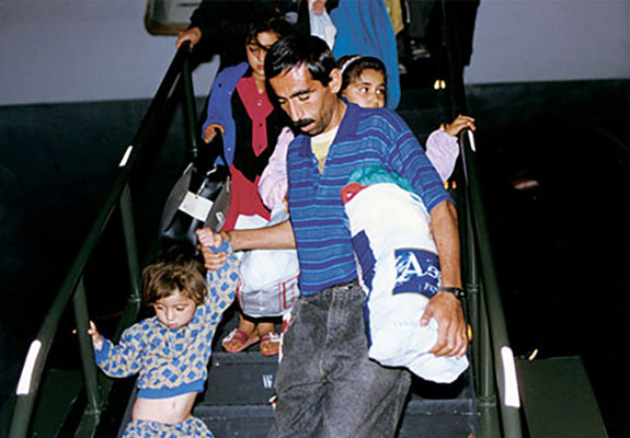 A father helps his daughter down the stairs of a plane. The Kurdish refugees had just completed a 17-hour flight from Turkey to Guam.
