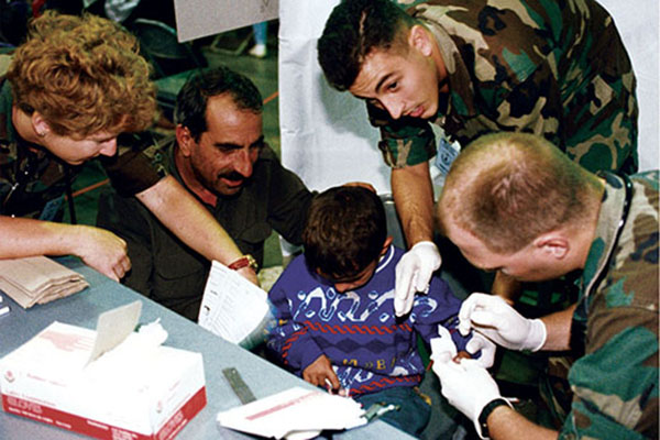 Medical personnel take a blood sample from a newly-arrived Kurdish boy who is being comforted by his father. The medical screening procedures were critical for getting approval to emigrate.