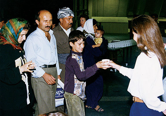 A volunteer escort meets a Kurdish refugee family upon arrival at Andersen AFB, Guam. The volunteer would help the family through customs, medical screening, and an initial INS interview.