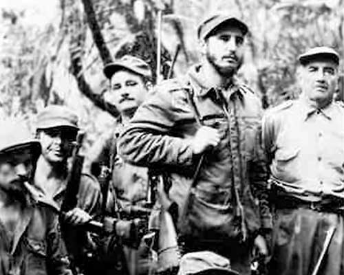 Conditions in the Sierra Maestra were harsh, but their remoteness allowed the guerrillas to easily detect incursions by government troops. Raúl Castro is kneeling with a telescoped rifle. His brother, Fidel, is standing directly behind him.