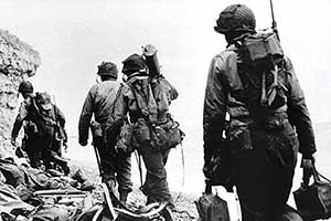 Rangers move along the beach carrying supplies and weapons for Force “A” at Pointe du Hoc.