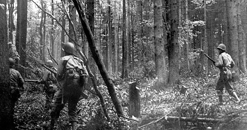 Infantrymen move cautiously through the densely wooded terrain of the Hürtgen Forest.