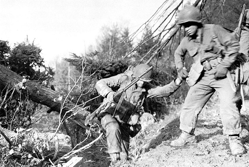 Infantrymen struggle up a wooded hillside
