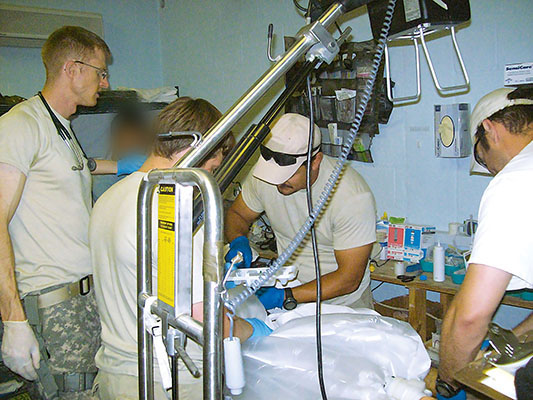 CPT Jamie Riesberg, an Afghan interpreter, a medic from the CJSOTF Civil Affairs Team, SSG Brian Moore, and CPT Ed Dunton attend a trauma patient.