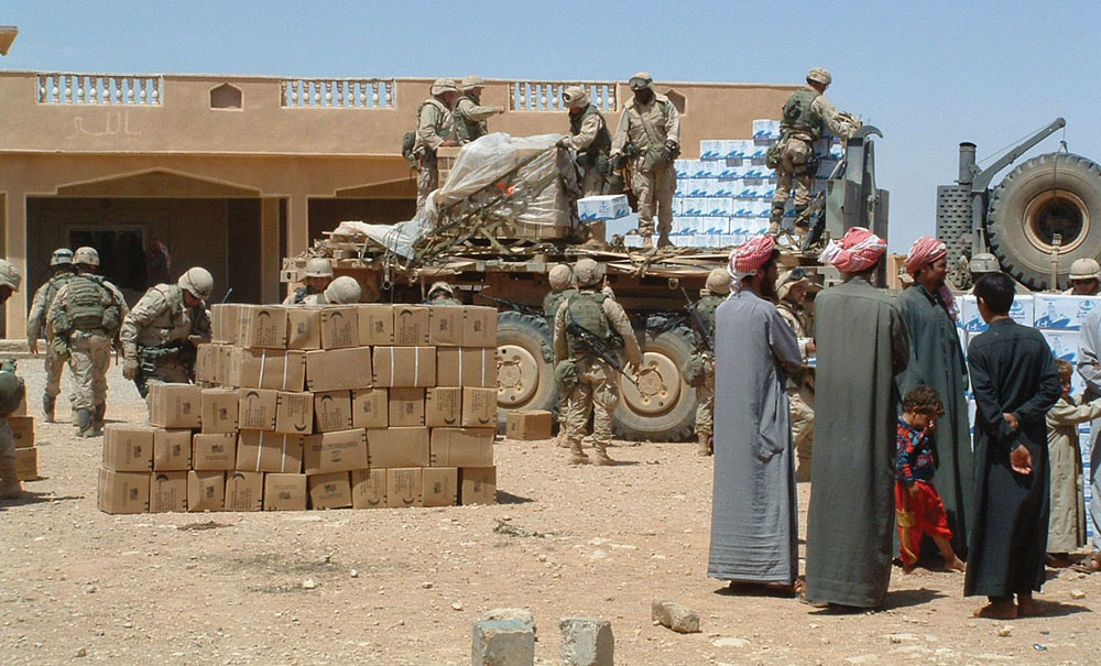 In western Iraq logistics soldiers unload humanitarian rations and water for a village near a forward operations base.