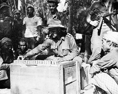 Civil Affairs officer British Captain Terence Carroll, assigned to NCAC, pays local villagers for war damage caused by the MARS Task Force.