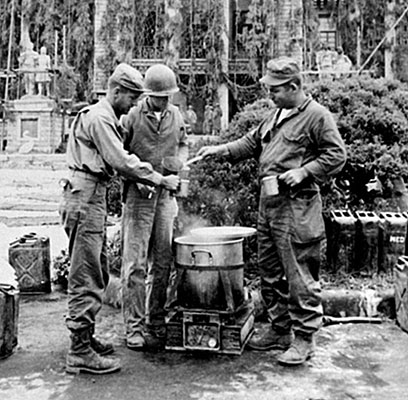 Members of TF INDIANHEAD set up their kitchen in front of the North Korean capitol building in P’yongyang, shown here in defensive camouflage. This building became Eighth Army Headquarters.