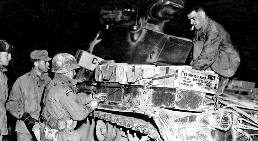 A WWII Ranger veteran loads ammunition aboard a tank prior to offensive operations.