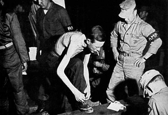 An emaciated American POW receives new clothing at the transfer station, Freedom Village, Panmunjom.