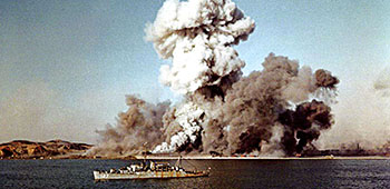 USS Begor (APD-127) in foreground of Hungnam harbor on 24 December 1950 as explosions ravage the port facility.