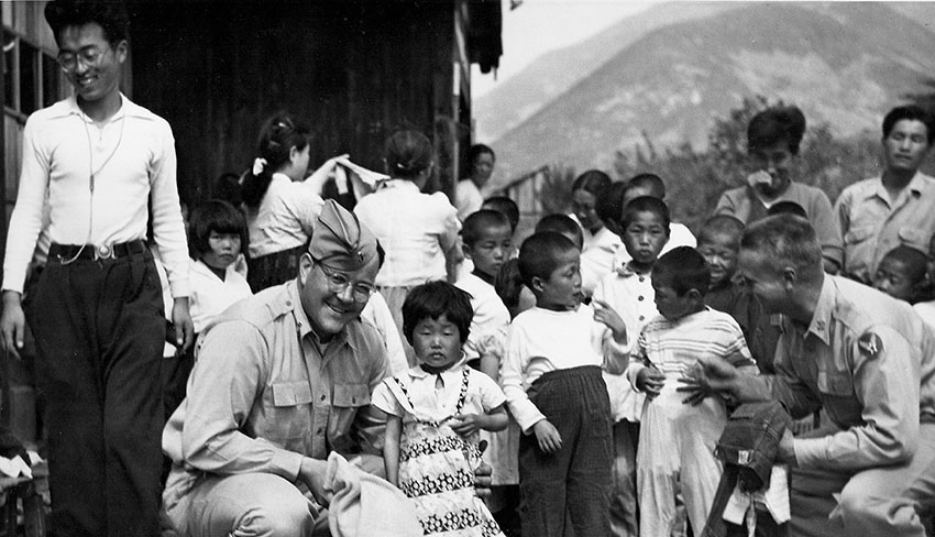 LT Donald F. Barris (left) and LTC William M. Hales of the 1903rd Engineer Aviation Battalion distribute clothing donated by the Officers’ Wives Club of Beale Air Force Base (California) to the Kupo Orphanage in 1952.
