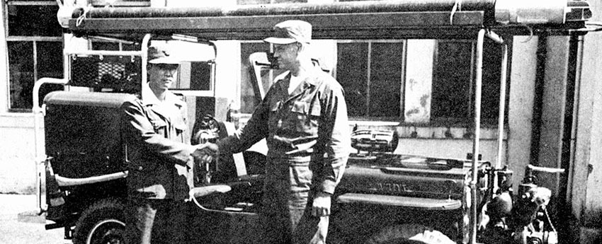 An UNCACK officer poses with a Jeep firetruck that was presented to the city of Taejon in October 1952.