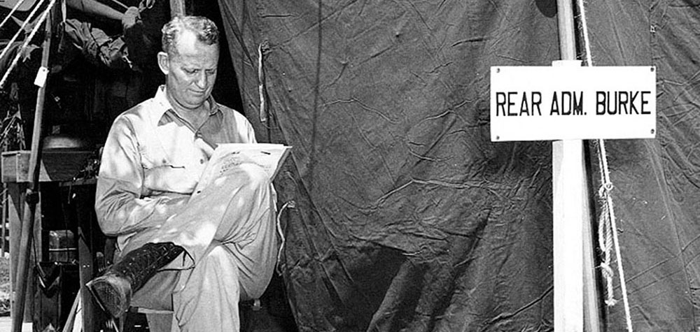 Rear Admiral Arleigh A. Burke reads outside his tent in the VIP area of the UN Base Camp near Munsan-ni.