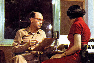 LTC Homer E. Shields, commander of the 1st Radio Broadcasting & Leaflet Group, reviews the script of a Chinese language radio broadcast with Lansa, a Chinese actress and linguist employed by the United Nations Command.
