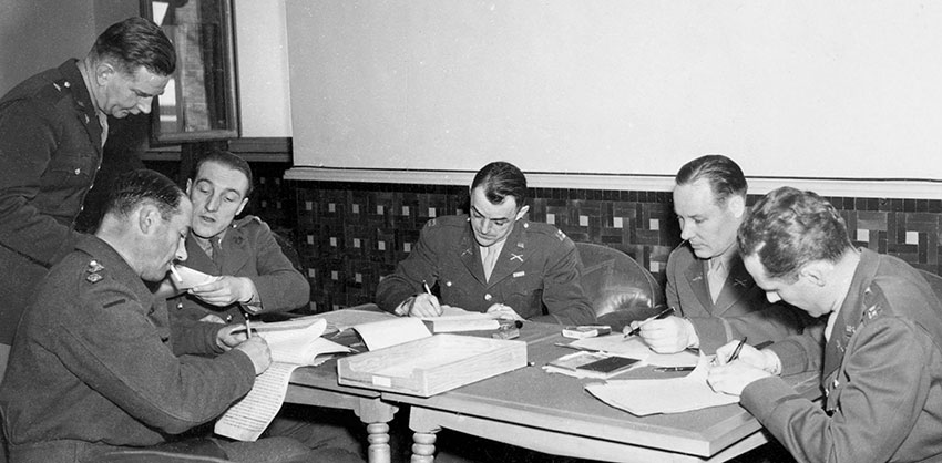 BG McClure, Chief of INC, confers with British censor COL Scott Bailey in January 1943 while others of the Censorship Branch inspect documents for sensitive information.
