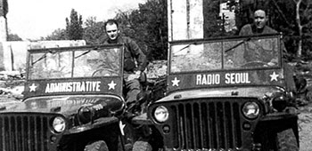 CPL Sig Front (Radio Seoul jeep) and CPL Herb Stevens (4th MRBC jeep) are posed inside the company compound in Seoul.