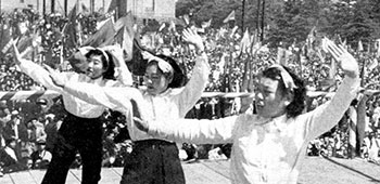 The May Day rally in Meiji Park began with entertainment by dancing girls and music. Spectators enjoyed ice cream cones and bean curd cakes while others waved festive, colorful banners.