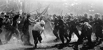 Communist rioters bearing steel-spiked spears, iron pipes, and clubs storm the Japanese police on Imperial Plaza.