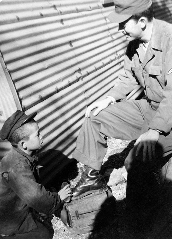 CPL Joe Dabney gets a boot shine outside the 4th MRBC enlisted quarters (Quonset hut) at <i>Radio Pusan</i> (Fall 1951).