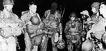 An unidentified FA Team preparing to jump into Camp Mackall as part of Field Training Exercise FREE LEGION in the summer of 1953.