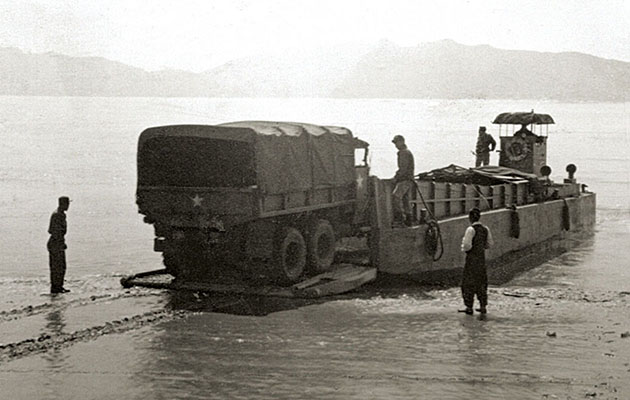 A Landing Craft Mechanized (LCM) loads a truck.