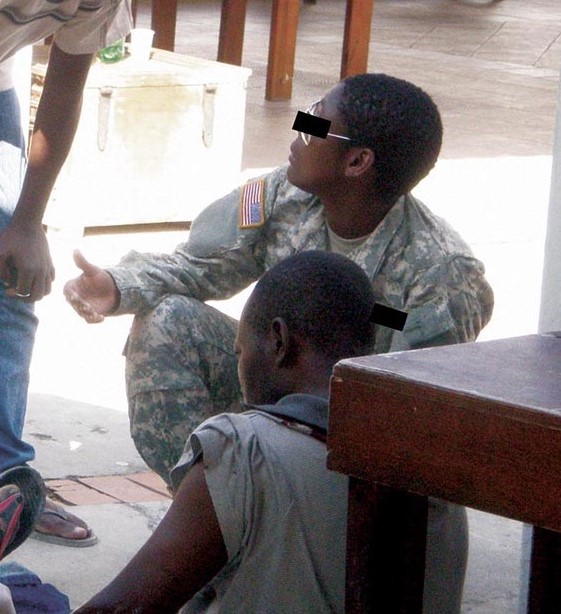 PFC Anse tending to the wounds of an injuried Haitian civilian.
