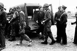 Forcemen receive coffee and doughnuts from the Red Cross at Santa Maria after the battle on La Defensa. The Forceman in the left center is wearing the wooden clogs issued as hospital shoes to those suffering trenchfoot or frostbite.