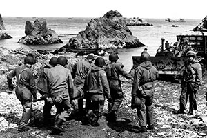 Evacuating a casualty on Kiska. U.S. casualties on Kiska were the result of friendly fire or injuries. A bulldozer pulls a tracked trailer of supplies ashore.