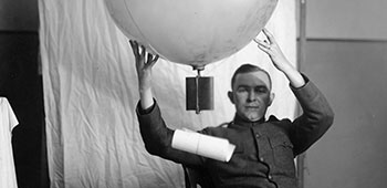 An AEF officer demonstrates an experimental timed fused system for releasing leaflets from a hydrogen-filled balloon. Limited research and development on balloon leaflet delivery occurred during the war, but dropping loose leaflets from fixed-wing aircraft was the method of choice.