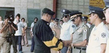 In 1981, Lieutenant Colonel Fry, Army Section Chief, U.S. Military Group, presents a baton passed in freefall by the ‘Jumping Ambassadors’ to the Honduran President, General Policarpo Paz García, on Air Force Day. The demonstration helped get presidential approval for an Mobile Training Team mission to train up a Honduran Military Free-Fall Team. 